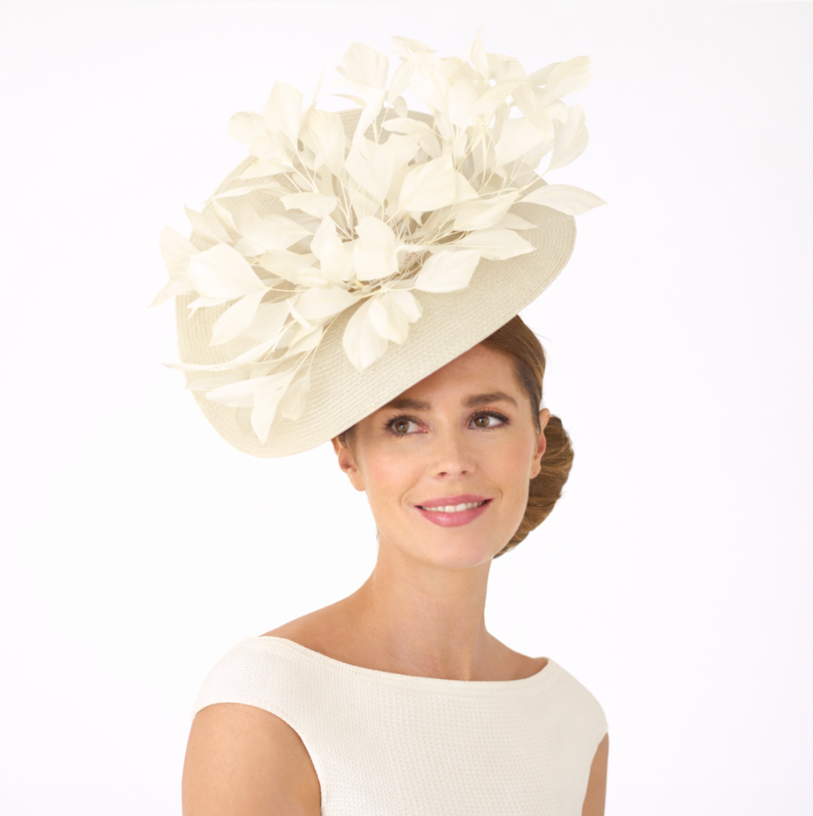 Woman wearing a large cream-colored floral hat on a white background
