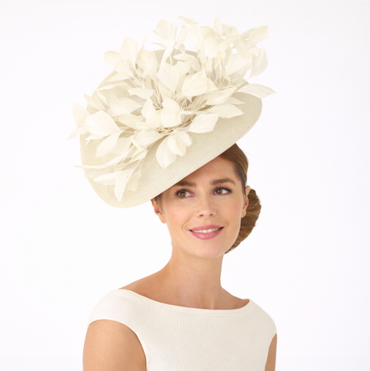 Woman wearing a large cream-colored floral hat on a white background