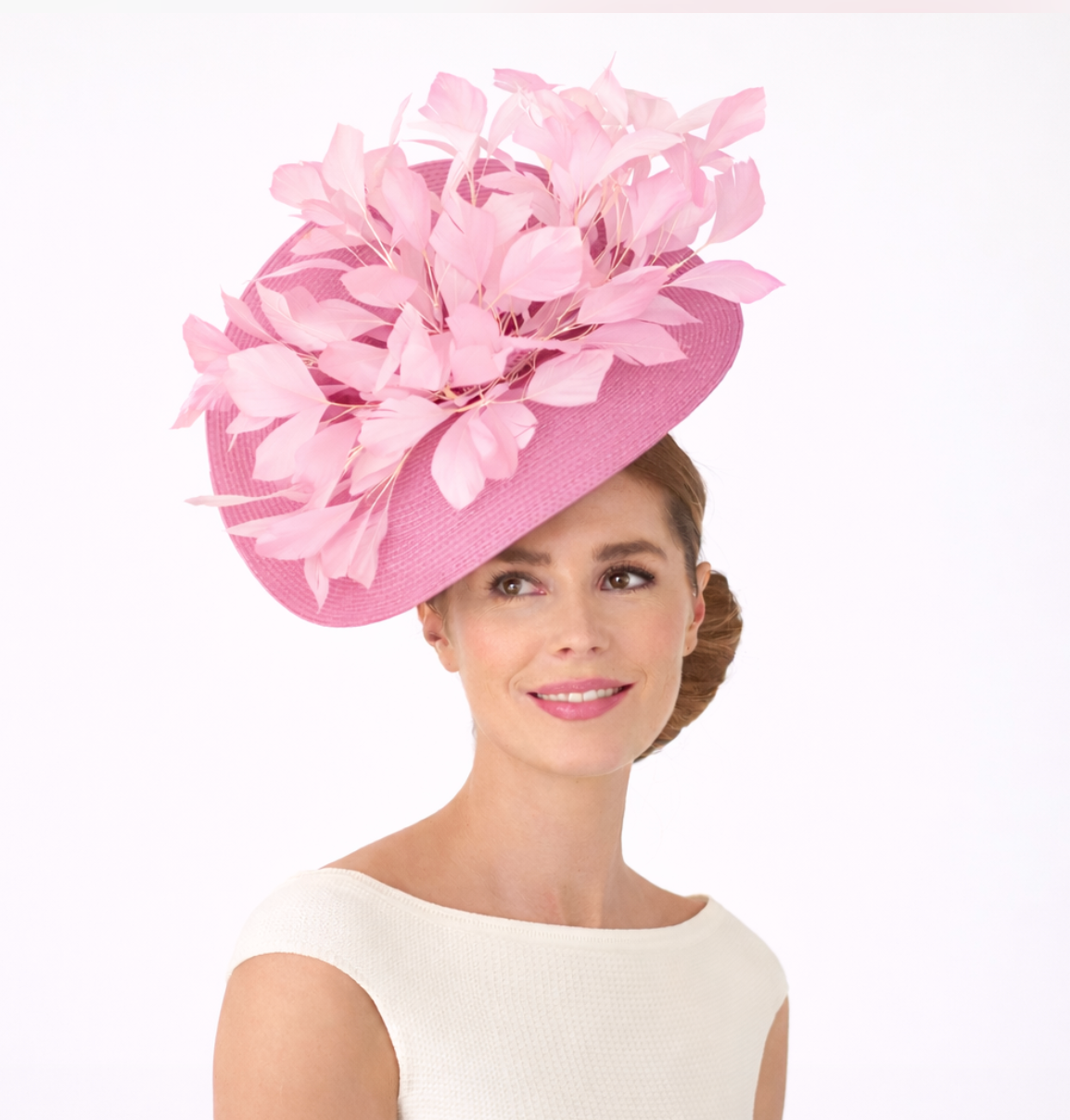 Woman wearing a pink decorative hat with feathers on a white background